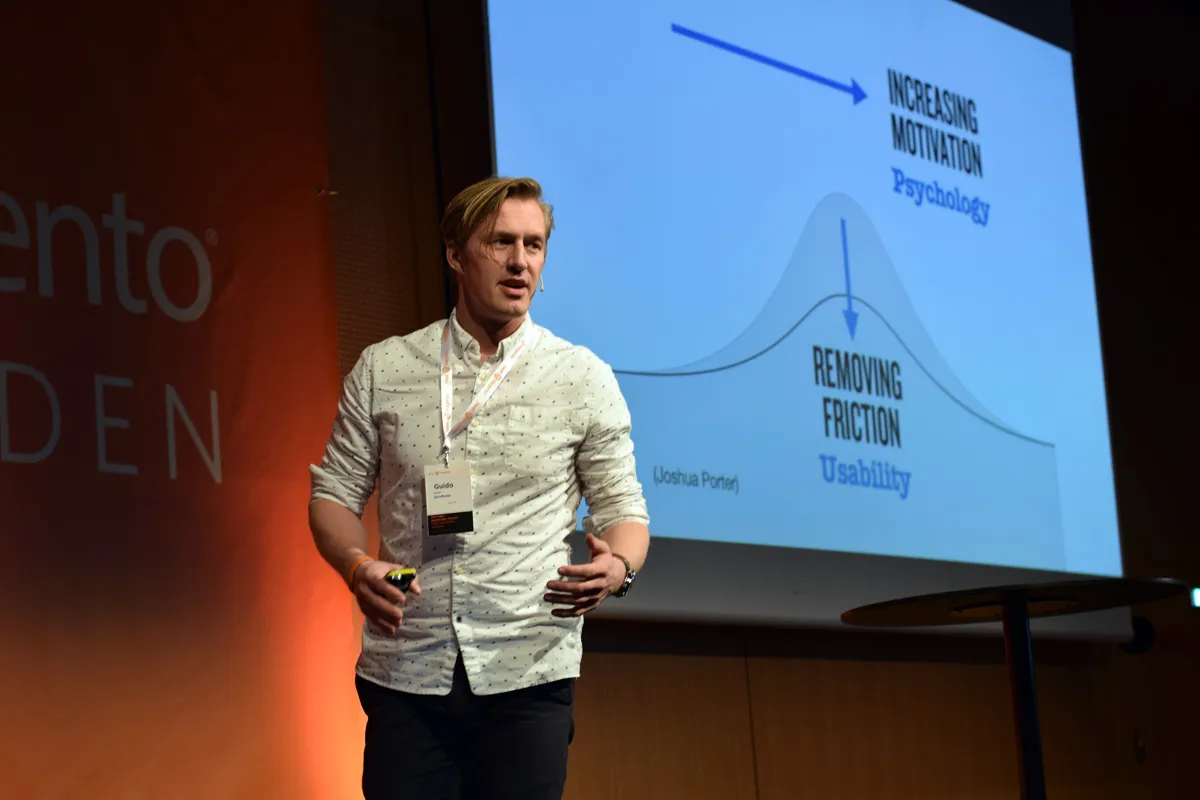 Guido Jansen föreläser på scen framför en bild om att öka motivation med psykologi och minska friktion med användbarhet